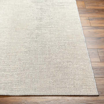 Close-up of the Medi Cream Area Rug showing its beige, woven texture and subtle pattern on a wood floor. Front