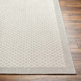 Close-up of Suzu Area Rug showing a geometric diamond pattern in beige, bone, and gray on a wood floor. Front
