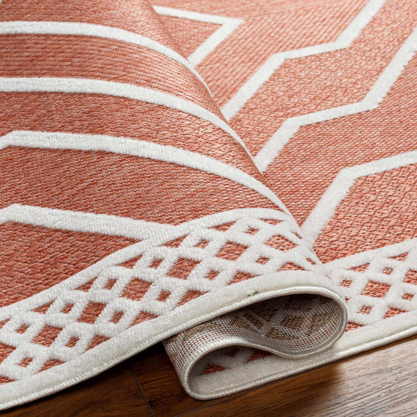 Close-up of the Anja Orange Outdoor Rug showing its clay color and geometric, southwestern-inspired design. Fold