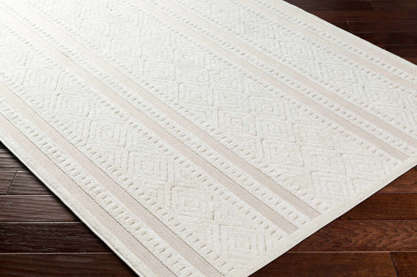 Close-up of the Enan Cream Outdoor Rug showing its geometric pattern and light peach stripes on dark wood floor. Corner