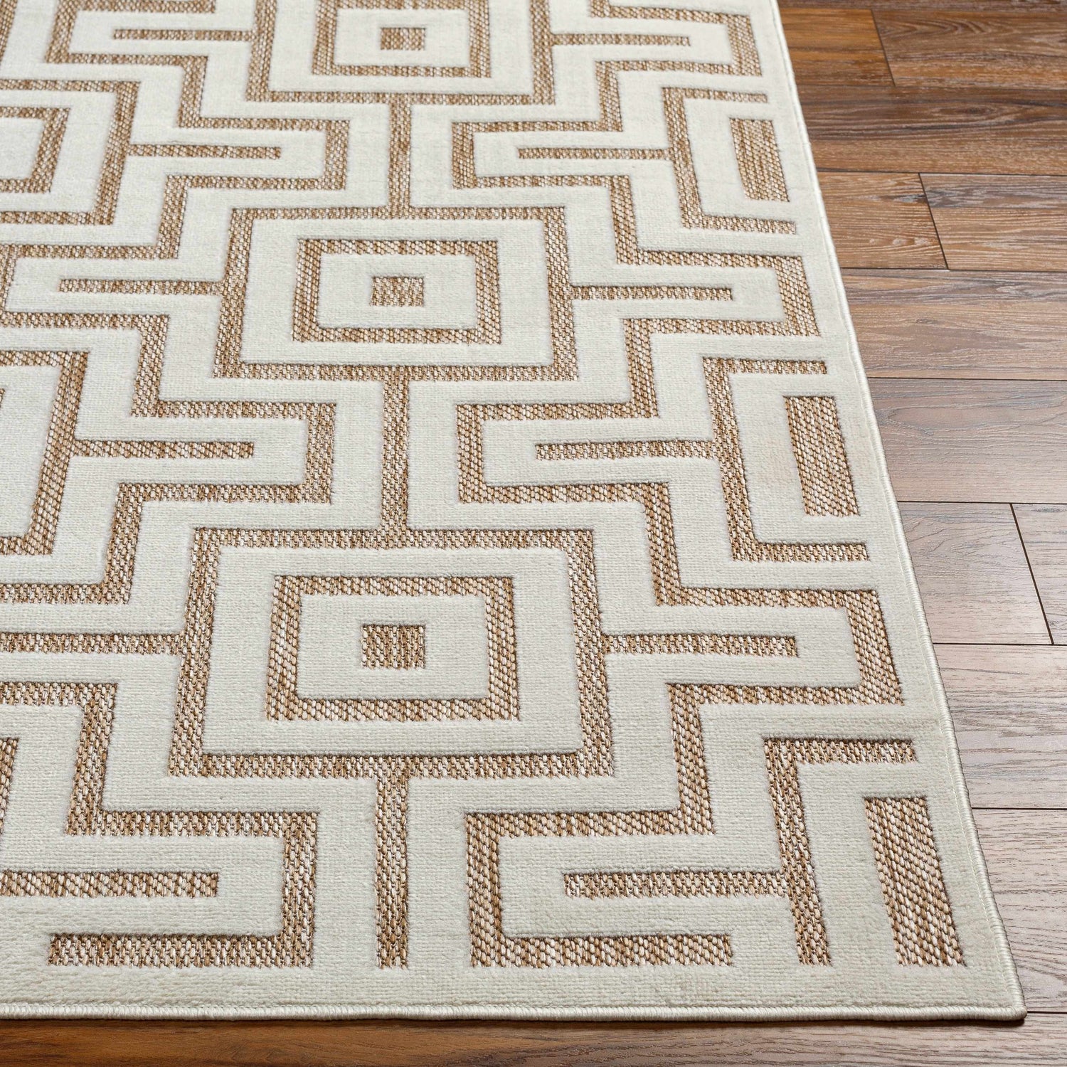 Close-up of Zevi Tan Outdoor Rug showing a geometric, square pattern in tan and cream on a wood floor. Contemporary style. Front