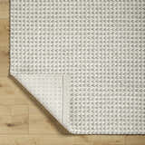Close-up of the Lenci Bone Area Rug showing its hand woven texture and contemporary beige and bone arrow pattern. Fold