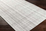 Close up of Jezel Beige Area Rug showing woven texture and subtle plaid pattern on dark wood floor. Corner