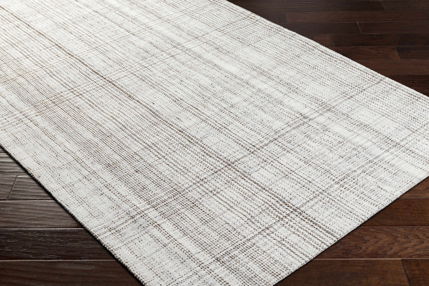 Close up of Jezel Beige Area Rug showing woven texture and subtle plaid pattern on dark wood floor. Corner