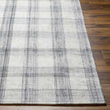 Close-up of the hand woven Leeba Gray Plaid Area Rug showing texture and pattern on dark wood flooring. Front