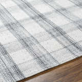 Close up of the Leeba Gray Plaid Area Rug showing the woven texture and gray and white pattern on a wood floor. Texture