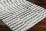 Close-up of the Gorou Taupe Area Rug showing its striped geometric pattern and soft texture on dark wood flooring. Corner