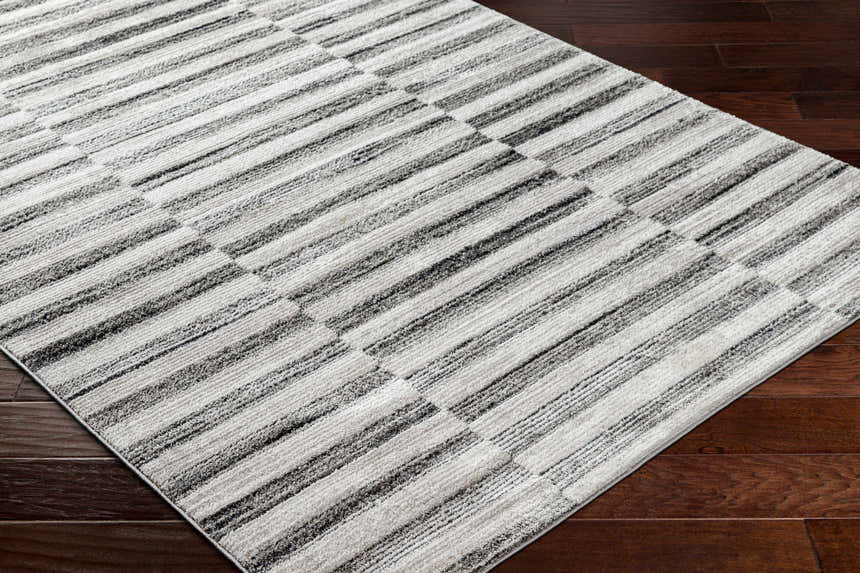 Close-up of the Gorou Taupe Area Rug showing its striped geometric pattern and soft texture on dark wood flooring. Corner