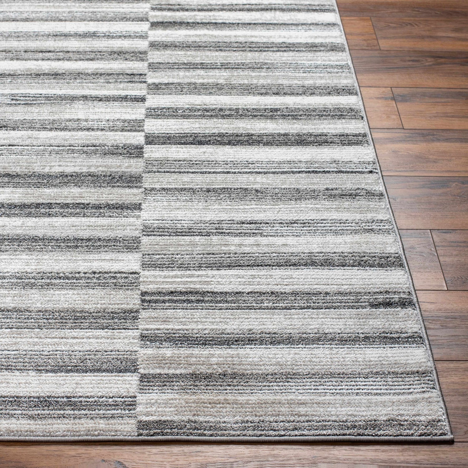 Close-up of the Gorou Taupe Area Rug showing a horizontal striped pattern in shades of gray and cream on hardwood flooring. Front