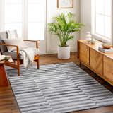 Living room scene with a Gorou Taupe Area Rug, gray armchair, wood media console, and indoor plant. Roomscene-Rectangle