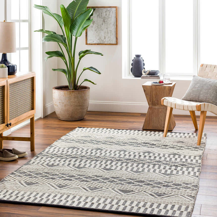Living room scene with a geometric Carly Area Rug in dark gray and off-white on hardwood floors. Contemporary style. Roomscene-Rectangle