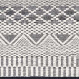 Close-up of the hand woven Carly Area Rug, featuring a geometric pattern in dark gray, nickel, off white, smoke, and taupe. Swatch