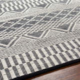 Close up of the Carly Area Rug, a hand woven wool rug with a geometric design in dark gray and off white. Texture