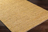 Close-up of Doris Beige Area Rug showing hand woven jute and cotton texture and neutral camel color on dark wood floor. Corner