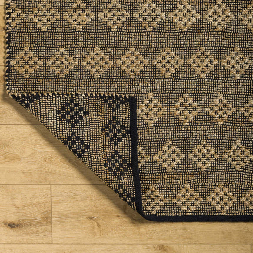 Close-up of the hand-woven Irina Area Rug. Medium brown and nutmeg jute and cotton blend with a traditional geometric pattern. Fold