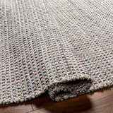 Close-up of the hand woven Beige Teal Aron Area Rug showing texture and pattern detail on a wood floor. Fold