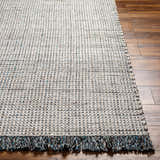 Close-up of the Beige Teal Aron Area Rug showing its woven texture and fringed edge on a wood floor. Front