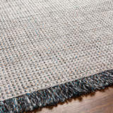 Close-up of the Beige Teal Aron Area Rug showing woven texture and charcoal, teal, and brown fringe. Texture