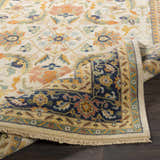 Close-up of the hand-knotted Starford Carpet. Farmhouse style rug with floral pattern in cream, blue, peach, and gold tones. Fold