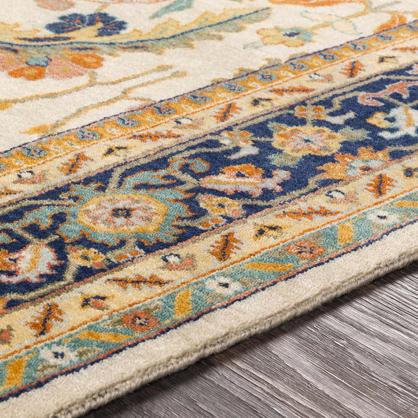 Close-up of the hand-knotted Starford Carpet. Cream rug with traditional floral pattern in navy, orange, and teal. 100% NZ Wool. Texture