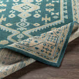 Close-up of the hand-knotted Stepps Area Rug, showcasing its aqua, beige, and teal bohemian design and wool texture. Fold