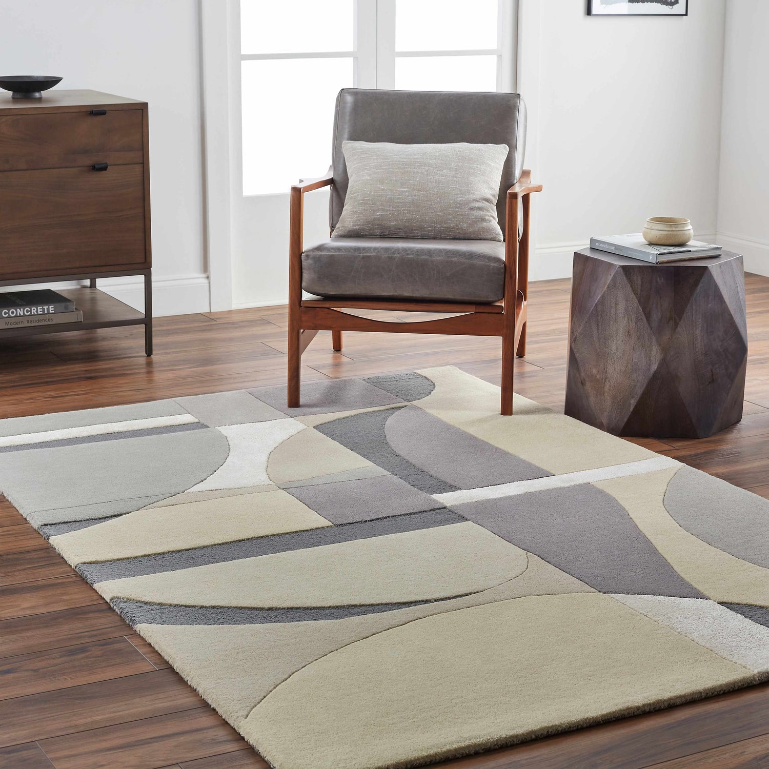 Contemporary living room scene with a beige and gray Duru Area Rug, wood floors, gray chair, and modern wood cabinet. Roomscene-Rectangle