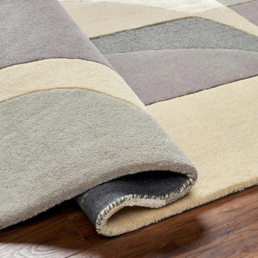Close-up of the hand-tufted Duru Area Rug, featuring a geometric pattern in beige and gray tones. 70% wool texture. Fold