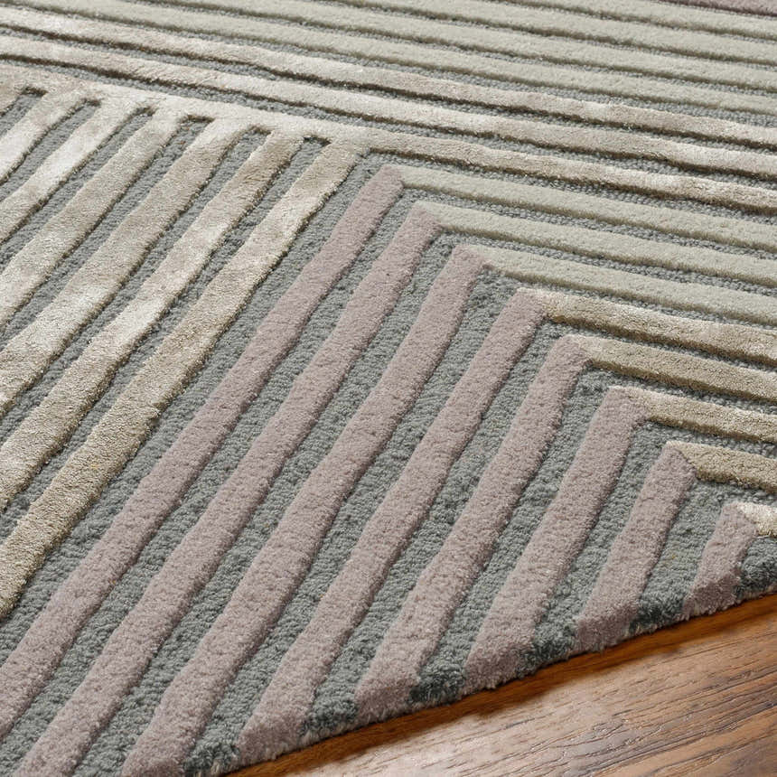 Close up of the Juan Area Rug showing beige, gray, and rose cream geometric pattern and wool texture. Texture