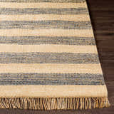 Close-up of Stapleford Striped Jute Carpet. Cream and navy stripes, natural jute texture, and fringe detail on dark wood floor. Front