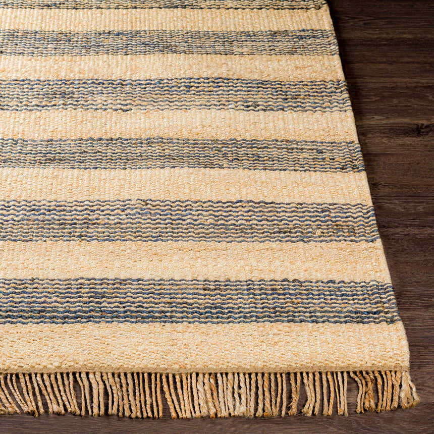 Close-up of Stapleford Striped Jute Carpet. Cream and navy stripes, natural jute texture, and fringe detail on dark wood floor. Front