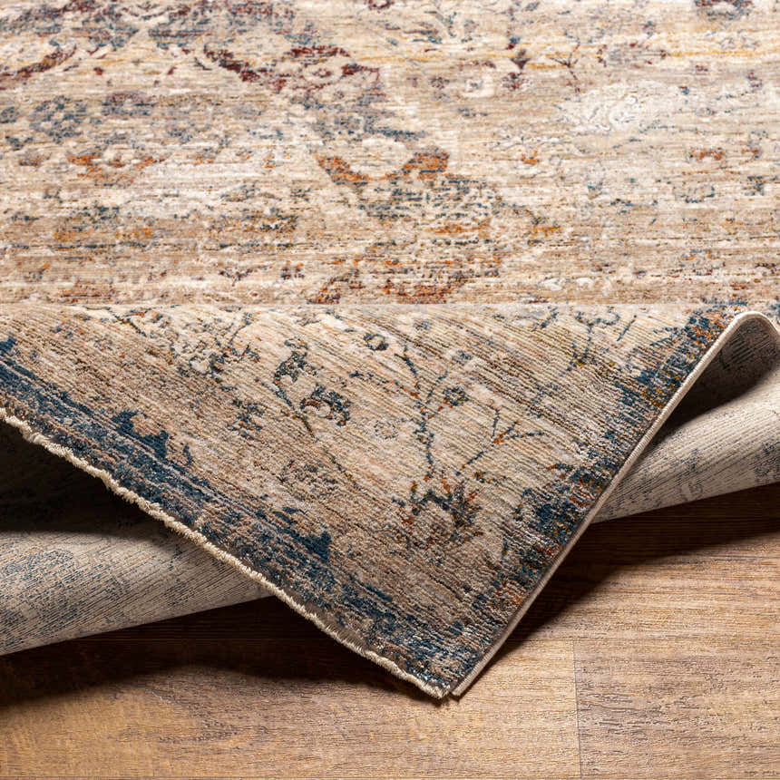 Close-up of the Stratmoor Area Rug showing its beige, blue, and brown traditional pattern and polyester texture. Fold