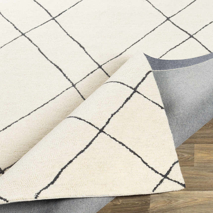 Close-up of the Strathalbyn Area Rug. Cream wool rug with a black geometric lattice pattern. Hand-tufted texture. Fold