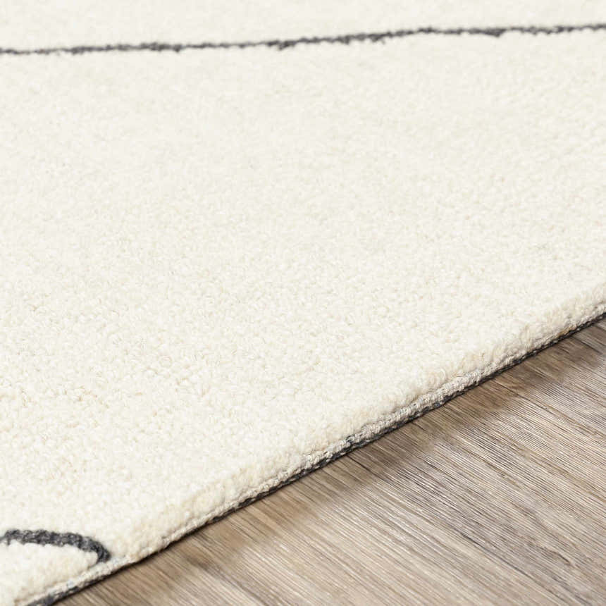 Close up of the Strathalbyn Area Rug. Cream wool rug with black geometric pattern and hand tufted texture. Texture