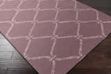 Close-up of Stroudsburg Area Rug in light gray and mauve with a trellis pattern on dark hardwood flooring. Corner