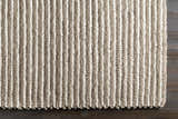 Close-up of the hand woven Sula Area Rug. Cream and gray wool rug with a striped pattern and textured design. Corner