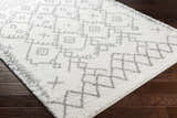 Close up of the Sutterton Area Rug. Cream rug with gray geometric pattern. Corner
