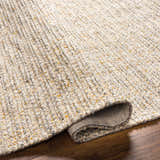 Close-up of the Amiel Beige Rug showing its hand woven texture, clay, dark gray, and light peach colors. Fold