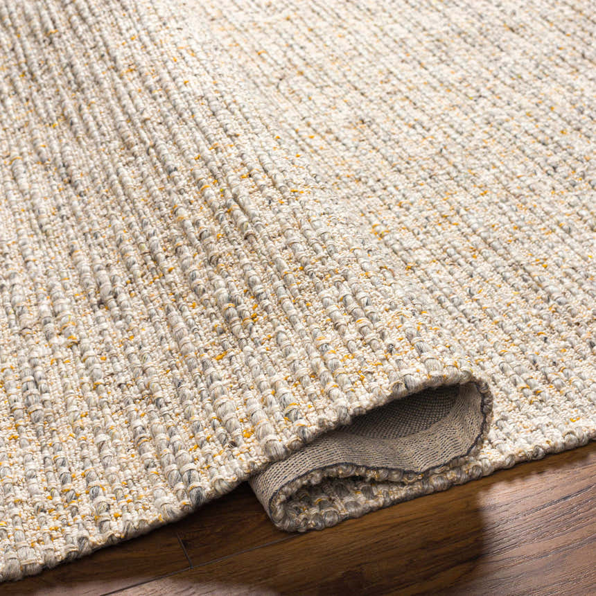 Close-up of the Amiel Beige Rug showing its hand woven texture, clay, dark gray, and light peach colors. Fold