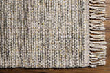 Close-up of the Amiel Beige Rug showing hand woven texture, clay, gray, and peach tones, and knotted fringe detail. Corner