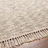 Close-up of Amiel Beige rug showing hand woven texture, neutral colors, and fringe detail on a wood floor. Texture