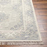 Close up of the hand woven Anund Area Rug with beige and dark gray geometric pattern and fringe. Front