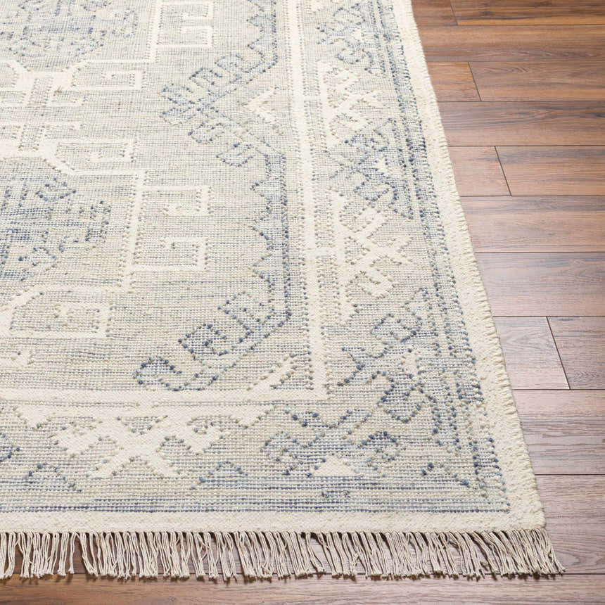 Close up of the hand woven Anund Area Rug with beige and dark gray geometric pattern and fringe. Front