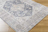 Close-up of the Keola Washable Area Rug. Farmhouse style rug with a traditional gray and beige pattern. Machine woven texture. Corner