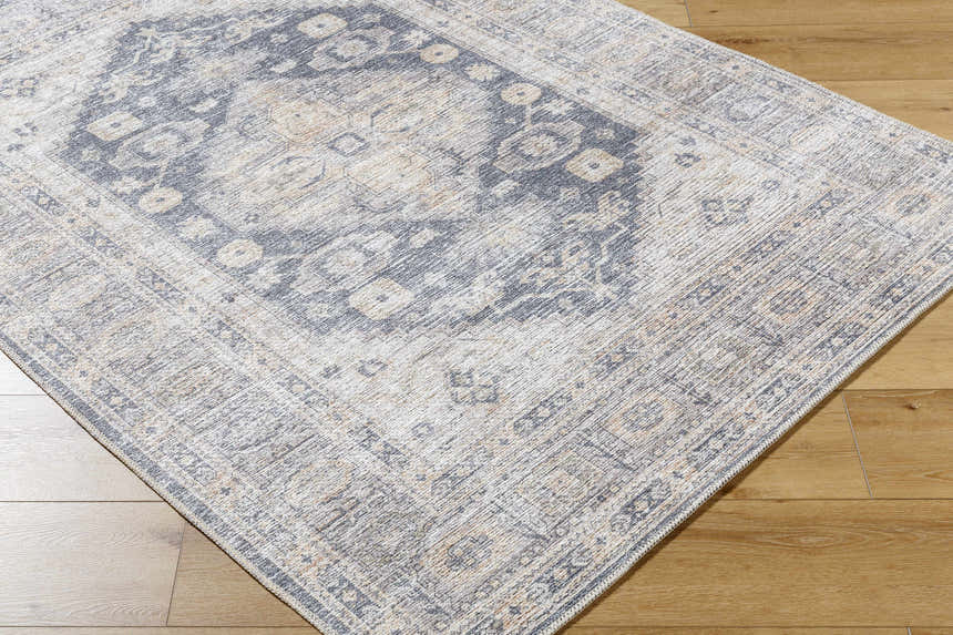Close-up of the Keola Washable Area Rug. Farmhouse style rug with a traditional gray and beige pattern. Machine woven texture. Corner