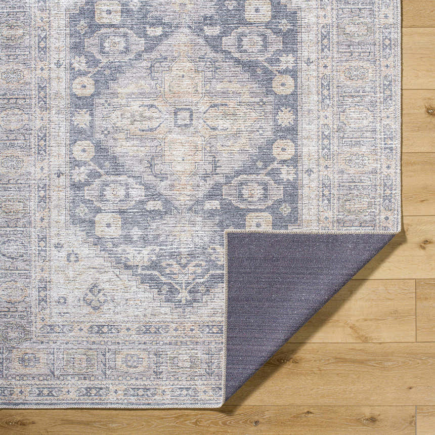 Close-up of the Keola Washable Area Rug showing its traditional, farmhouse-style pattern in blue, gray, and beige tones. Fold
