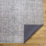 Close-up of the Orsin Washable Area Rug showing its traditional, farmhouse pattern and colors on light wood flooring. Fold