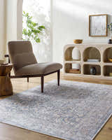 Living room scene with a blue and beige Orsin Washable Area Rug, gray chair, and light wood accents. Farmhouse style. Roomscene-Rectangle