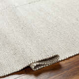 Close-up of the hand woven Abhay Beige Wool Area Rug showing texture and detail on hardwood floor. Fold