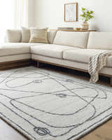 Living room scene with a light silver Sabah Area Rug, off-white sofa, and minimalist decor. Roomscene-Rectangle