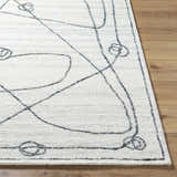 Close up of the Sabah Area Rug, a hand-tufted rug with a light silver and off-white abstract design. Cotton and wool texture. Front